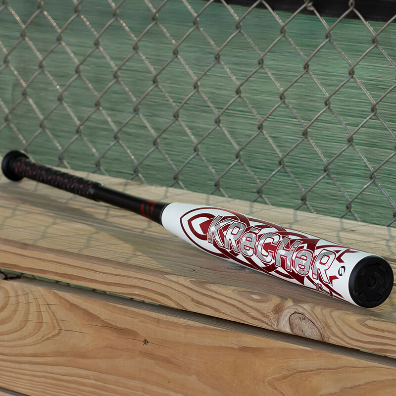 A white/red Worth KReCHeR Gamer Senior bat on a bench in a dugout - SKU: WSS4KGL